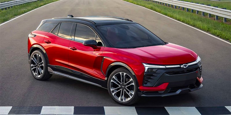 Red Chevrolet Blazer EV with a black roof parked on a racetrack with checkered markings.